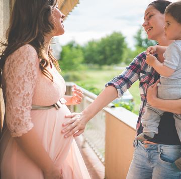 friend with child touching pregnant woman's belly