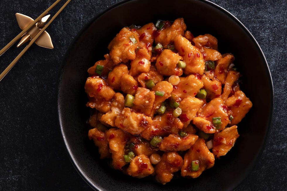 bowl of orange chicken with green onions and chili flakes