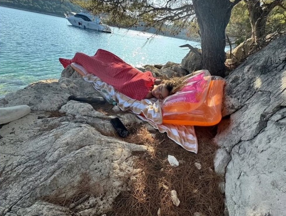 Person, die auf einem felsigen Strand in der Nähe von Wasser mit schwimmender Lounge ruht