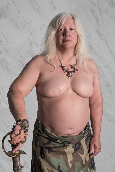 michelle robison holding a gold sword with no shirt on and camo skirt with tears running down her face