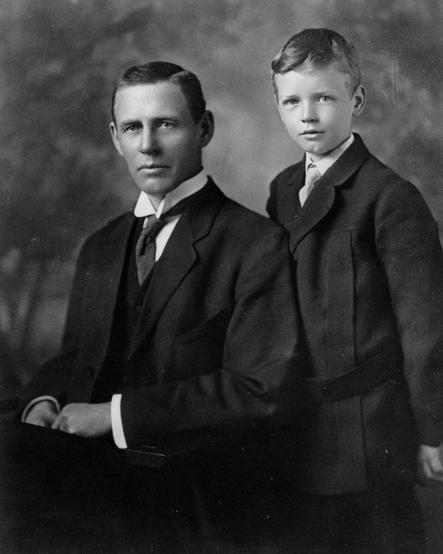 young charles lindbergh stands right of his father charles august lindbergh who is seated, both wear suits with ties