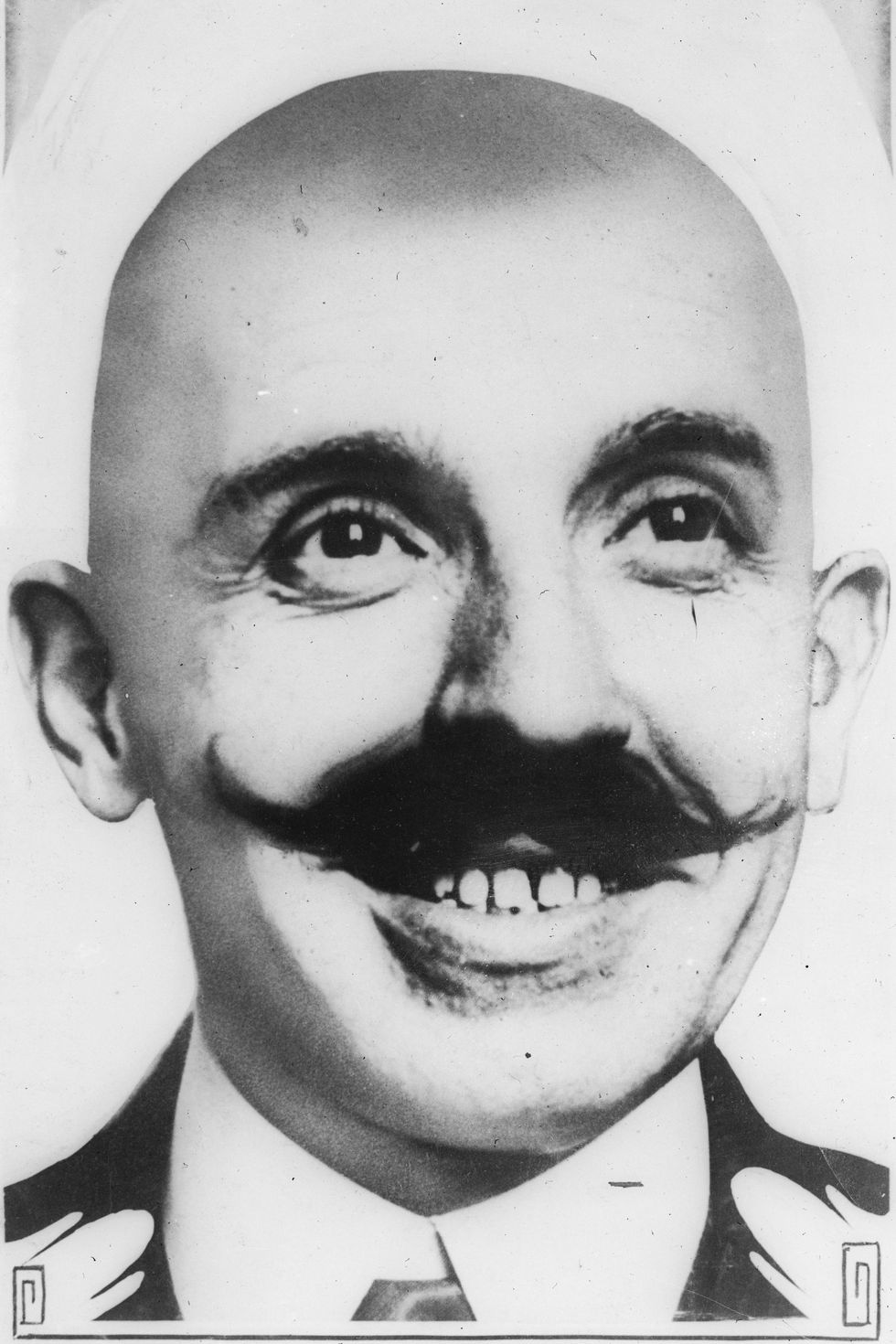 a man with a bald head and a prominent mustache smiles at the camera