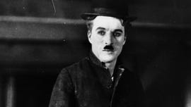 charlie chaplin wears a top hat and looks to the left