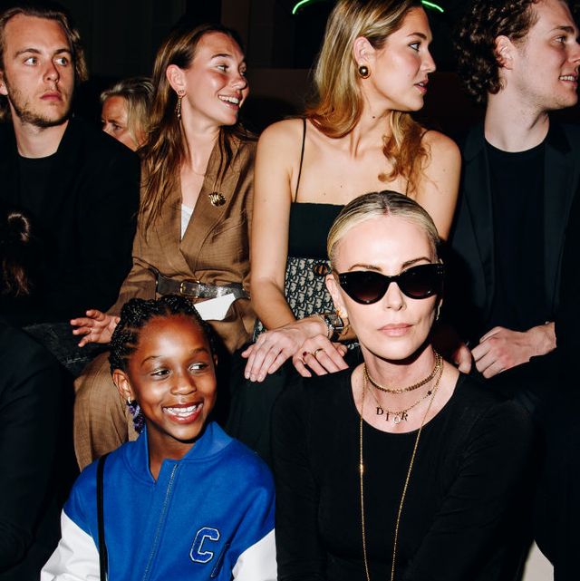 charlize theron and her daughter august theron at the dior pre fall 2024 charlize is dressed in black and nude colours while her daughter is wearing a bright blue and white baseball jacket
