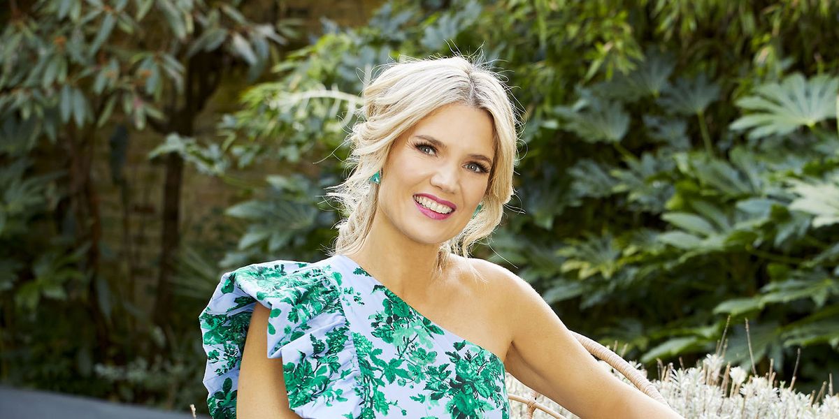 charlotte hawkins sits in a chair in a garden wearing blue and green dress