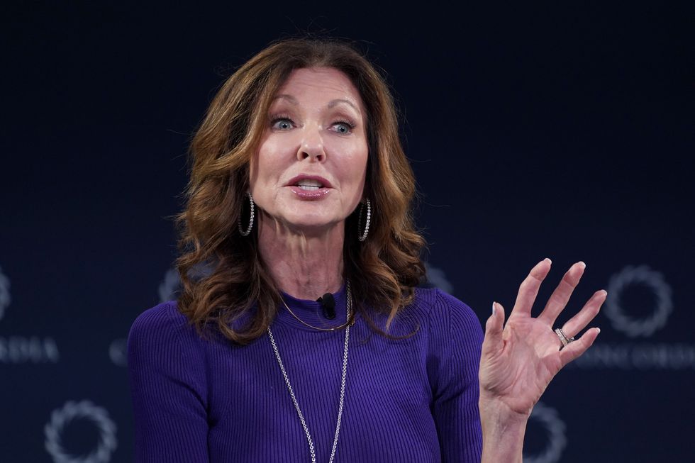 woman in a purple suit gesturing with her hand as she is speaking