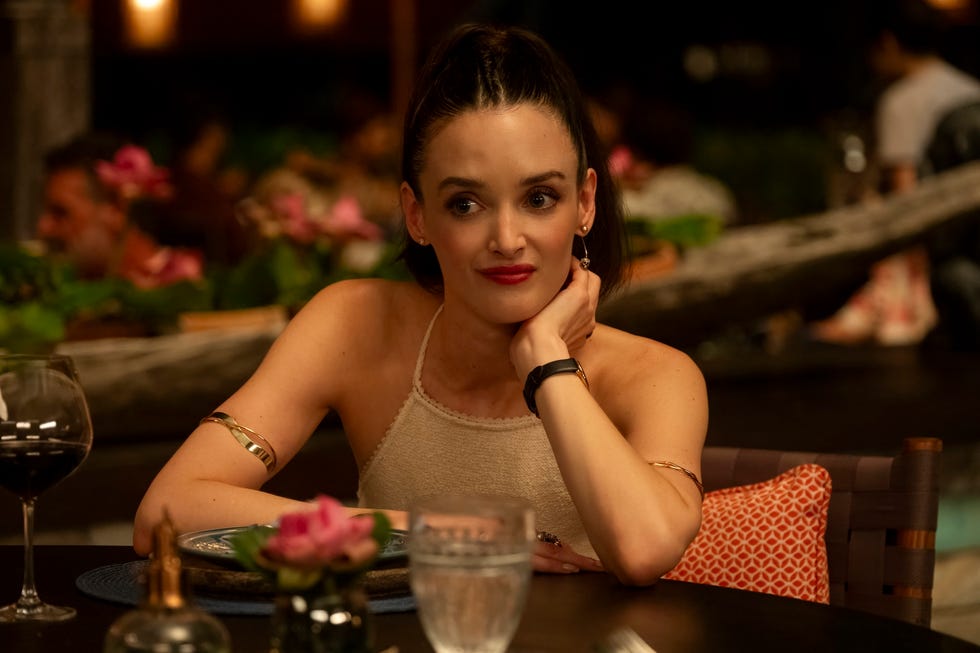 Woman sitting at a dining table with a glass of wine and flowers engaged in thought