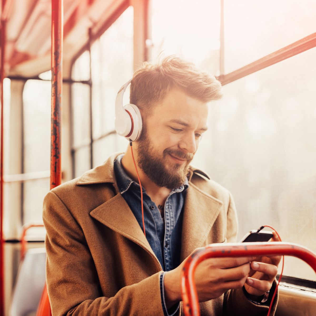 Charming man listening to music with headphones on a public bus