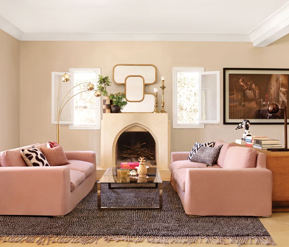 Living room with pink sofas, beige walls, rug with fringe