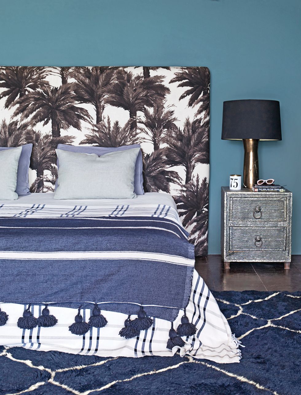 Bedroom with upholstered palm headboard and blue rug