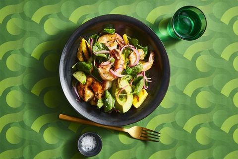 charred shrimp and avocado salad with red onion in a dark bowl