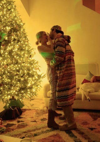 couple embracing in a cozy indoor setting with a decorated christmas tree