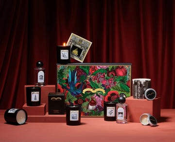 collection of luxury candles and perfumes displayed on a colored backdrop