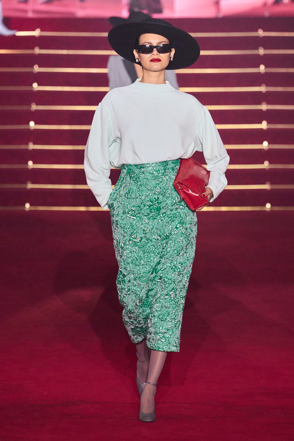 Şık bir kıyafet giyerek podyumda yürüyen moda modeli