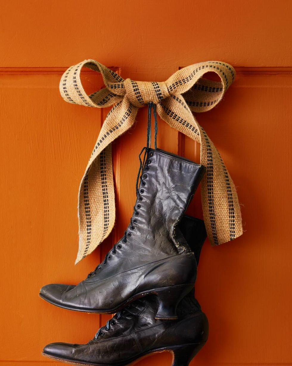 black victorian stlye boots hung on an orange door with burlap ribbon
