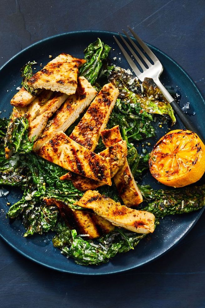 grilled lemon chicken with kale and lemon on a blue plate