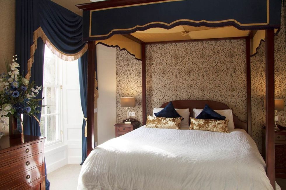 a room with a big four poster bed and thick drapes