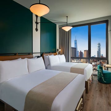 a couple of double beds in a room with a window showing the skyline