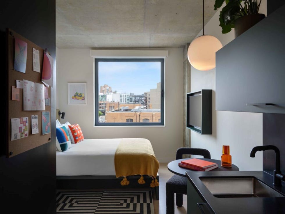 a bedroom with a small table and kitchen sink
