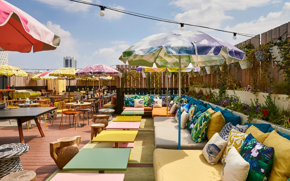 a patio with umbrellas and comfy colourful seating at mama shelter east