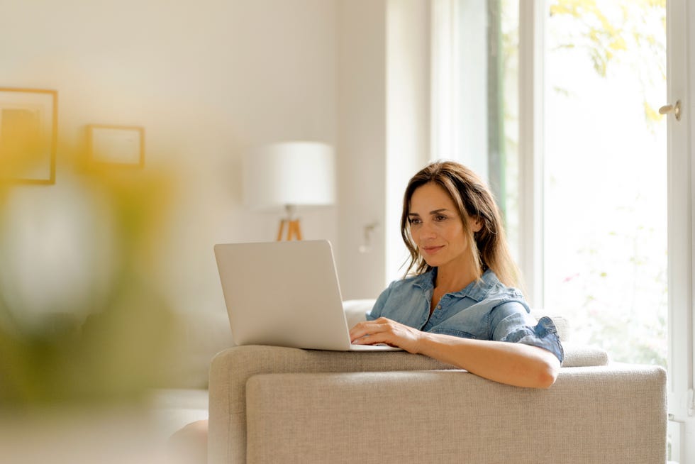 person using a laptop while sitting on a sofa in a welllit room