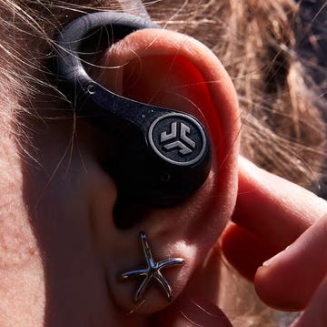 wireless earbud positioned near an ear with a hand adjusting it wireless earbud positioned near an ear with a hand adjusting it