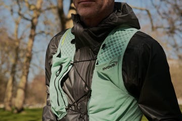 close up of a faceless man wearing a green running vest and grey raincoat