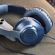 This is an image jbl headphones next to gaming controller on couch