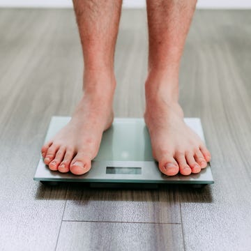 checking his weight on the electronic weighing scale