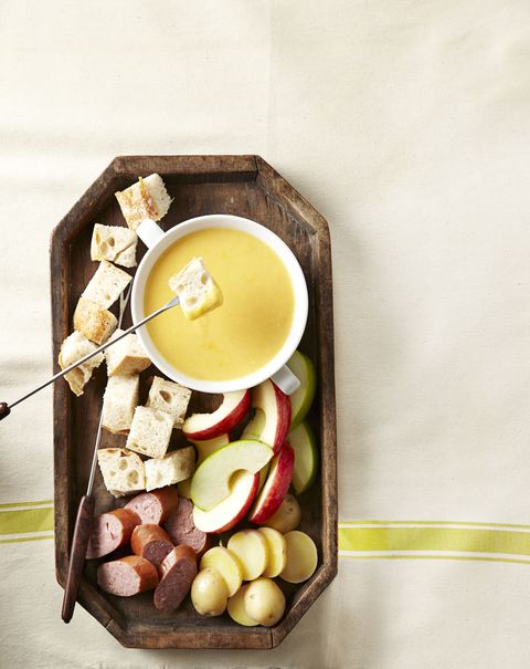 wooden platter of cheddar beer fondue and dipping food
