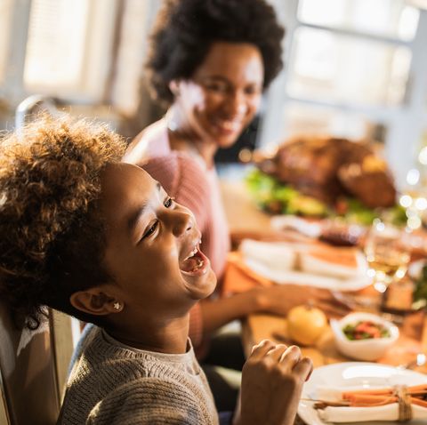 cheerful african american girl with her parents at dining table