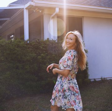 cheerful blonde woman looking over shoulder while walking at the backyard