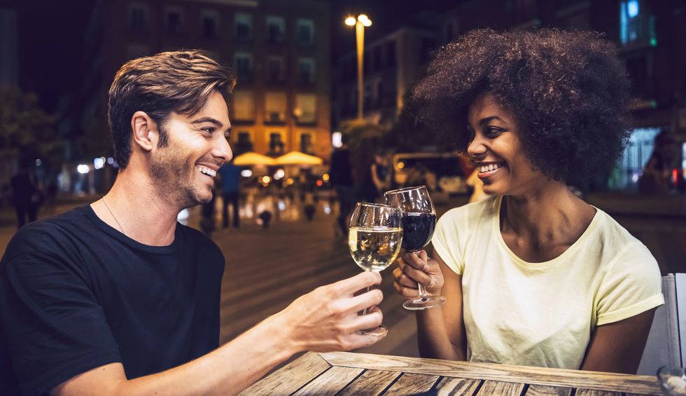 cheerful couple looking at each other while toasting wineglasses at date night
