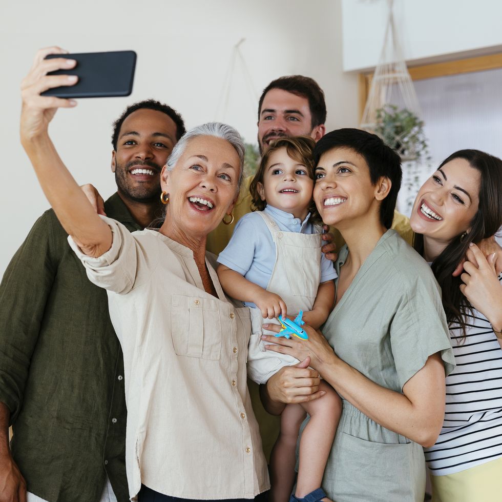 cheerful family taking selfie with smart phone in kitchen