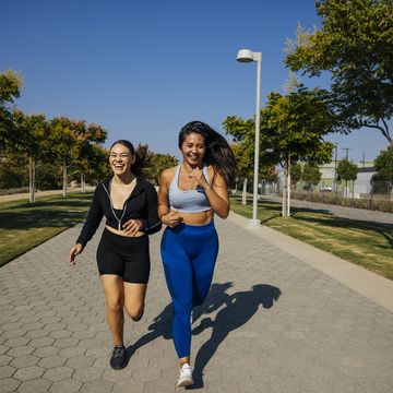 cheerful female friends running on footpath at park