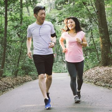 cheerful japanese couple running outdoors in a park