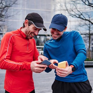cheerful male athletes comparing fitness apps on smartphones
