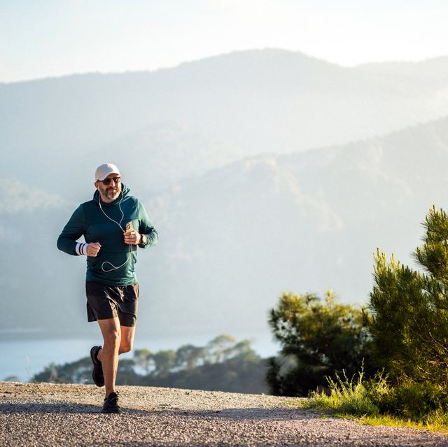 cheerful man jogging in mountains at sunset