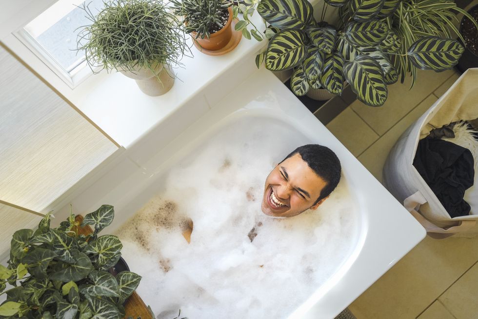 cheerful man taking bath in bathtub at home