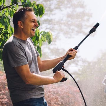 cheerful man with garden hose at back yard
