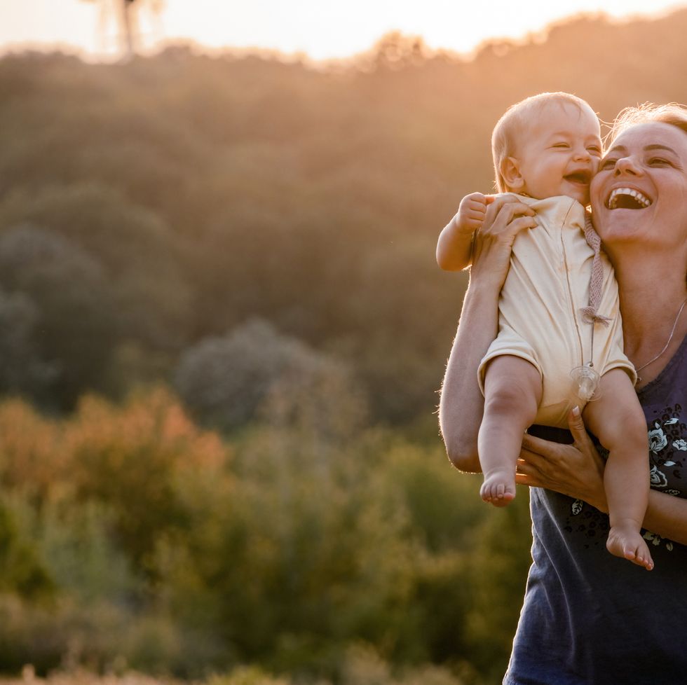 cheerful mother and baby girl having fun in nature at sunset.