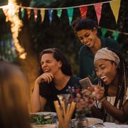 cheerful multiethnic friends enjoying at table during dinner party in backyard