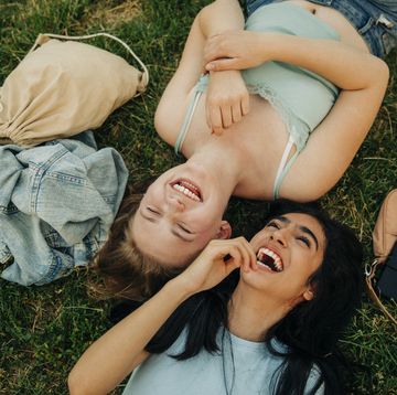cheerful teenage girls lying together at park