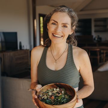 cheerful vegan woman eating a vegetable salad from a bowl