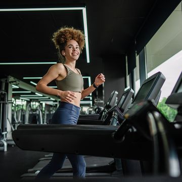 cheerful woman checking smartwatch during treadmill run.
