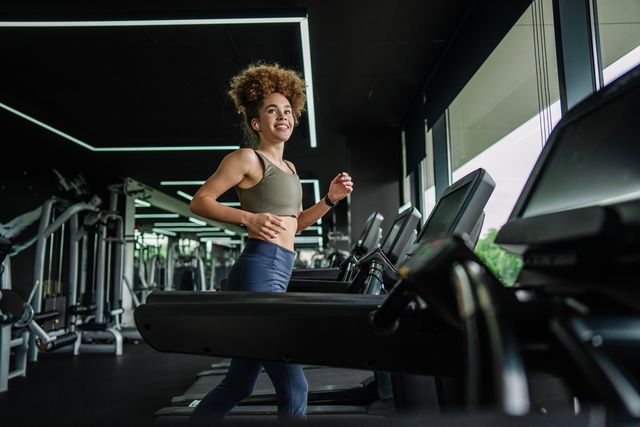 cheerful woman checking smartwatch during treadmill run.