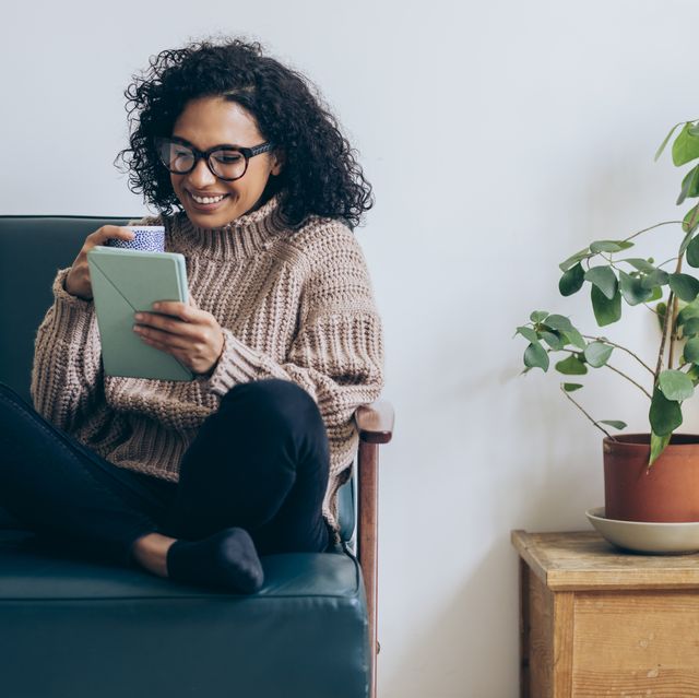 cheerful woman drinking coffee and using a digital tablet