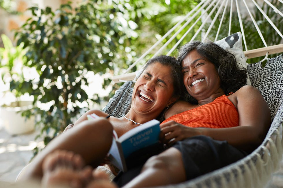 cheerful woman lying with mother in hammock