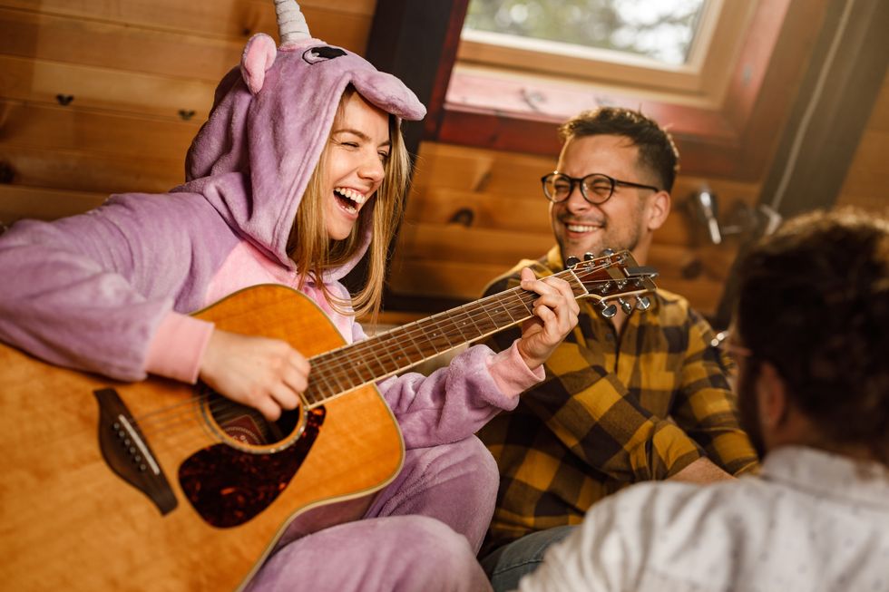 cheerful woman playing a guitar dresses as unicorn