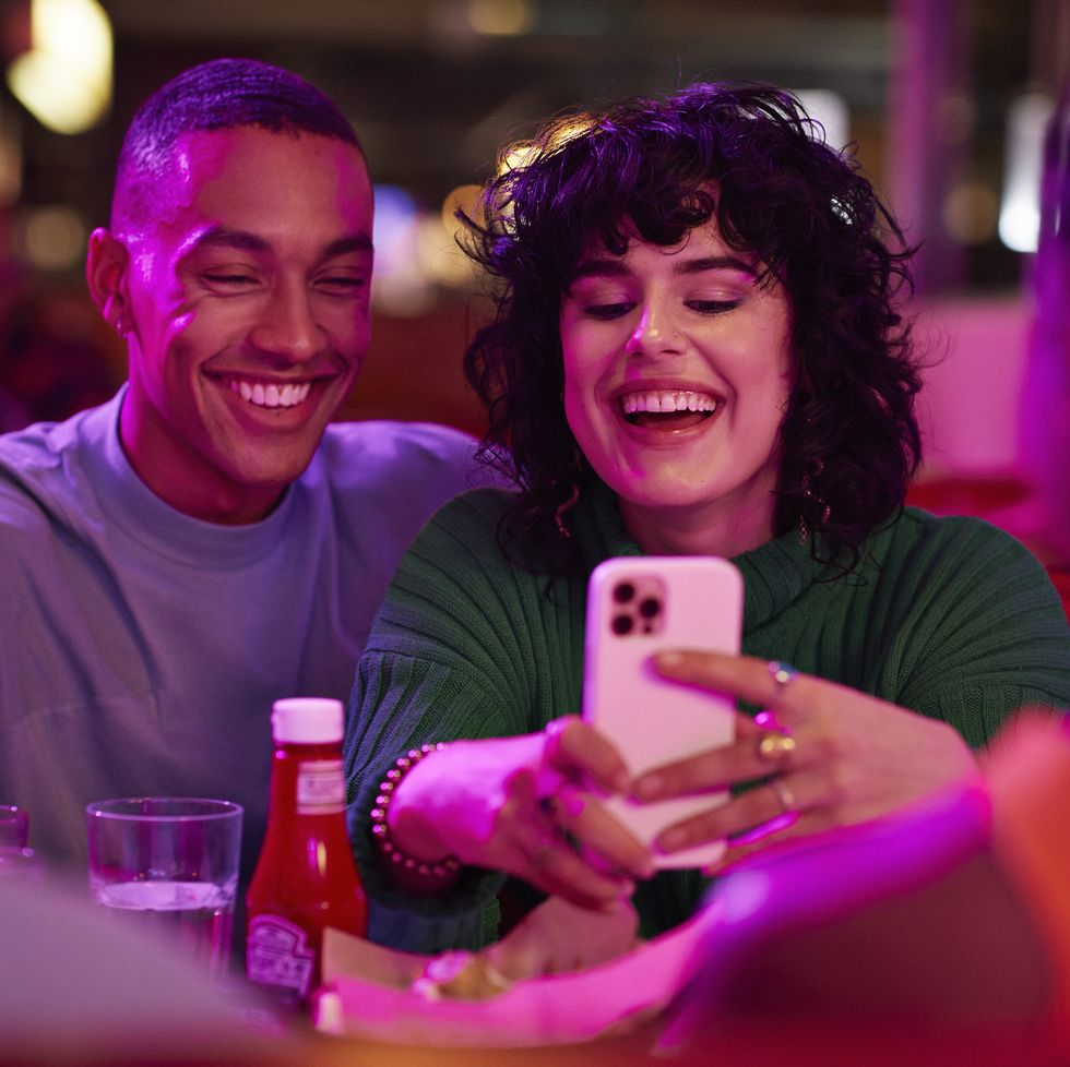 cheerful woman taking selfie with man